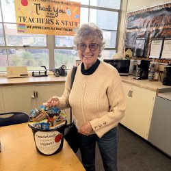 Teacher smiling while holding a basket of gifts for teacher appreciation week