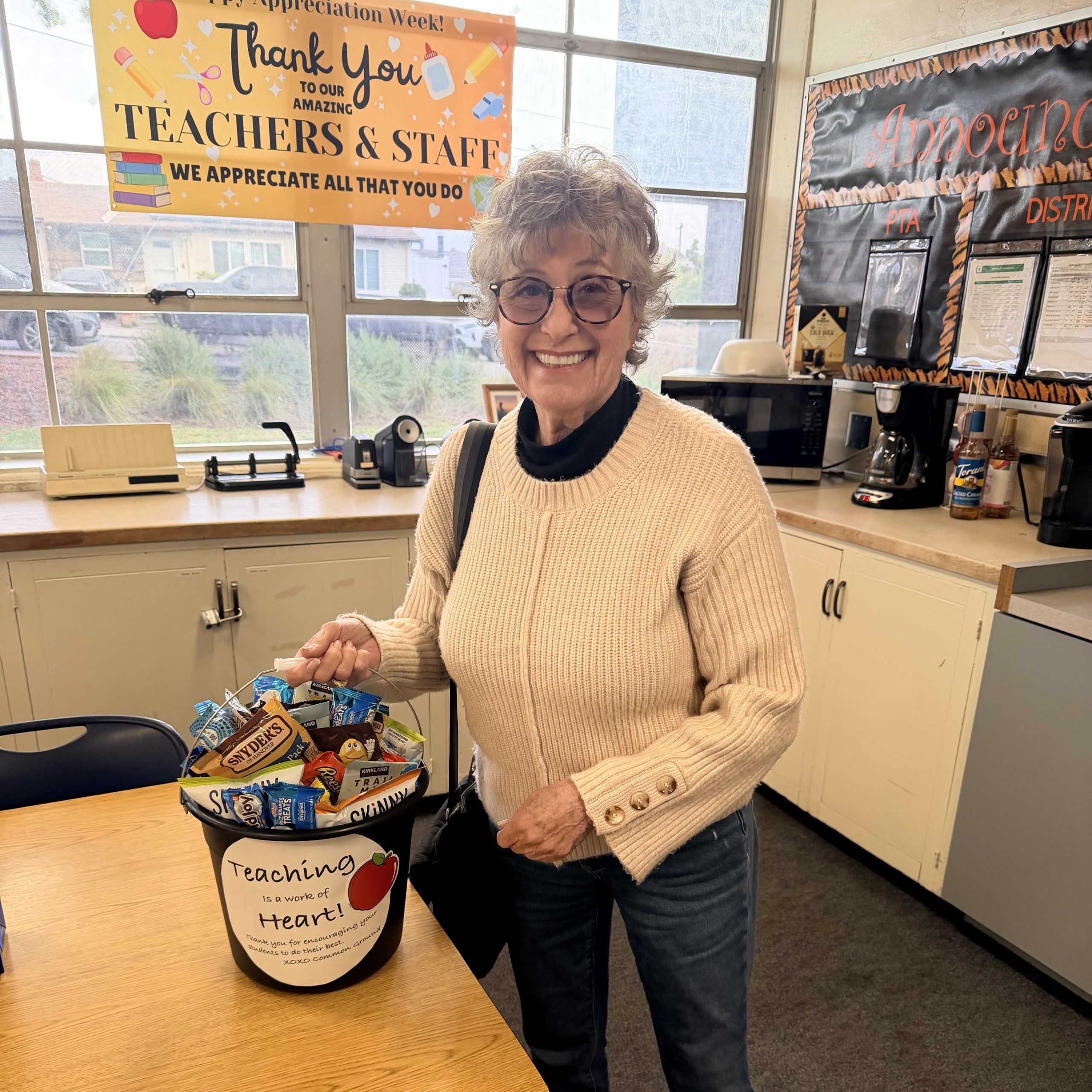 Teacher smiling while holding a basket of gifts for teacher appreciation week