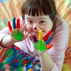 Down Syndrome Girl With Finger Paint Smiling