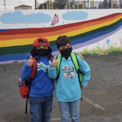 Two students giving thumbs up in front of the newly painted playground mural