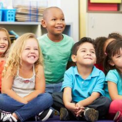 Group Of Students Sitting On Carpet C Happy And Smiling