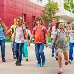 Group Of Young Students Holding Hands And Smiling While Walking