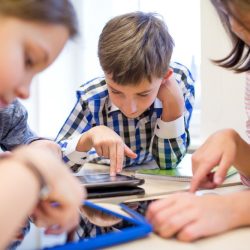 Kids Smiling While Using Tablets At Table