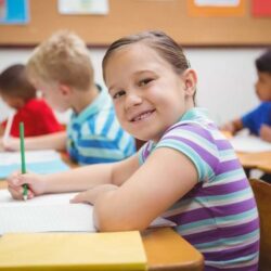 Smiling Female Student At Desk C Writing