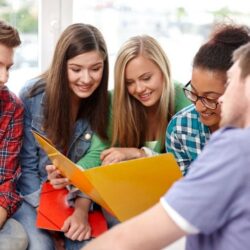 Group Of Students Smiling While Looking In Folder