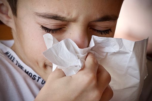 boy blowing nose into tissue