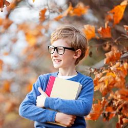 Autumn Boy With Glasses Smiling While Holding Books In The Fall