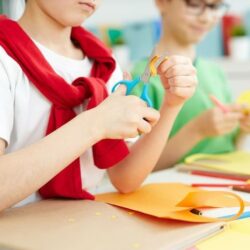 Student Cutting Construction Paper With Scissors