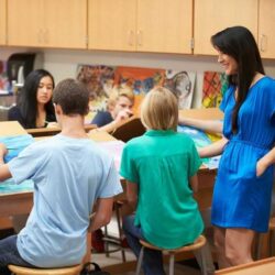 Kids In Art Class Painting With Teacher Helping