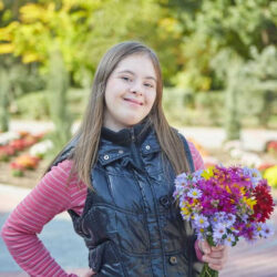 Downsyndrome Girl Holding A Boquet Of Flowers And Smiling