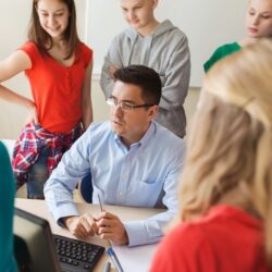 Teen Students Standing Around Male Teacher While Talking