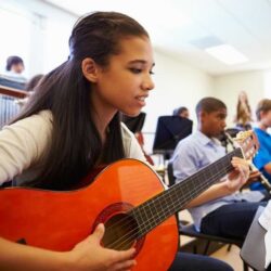 Girl Student Smiling While Playing Guitar