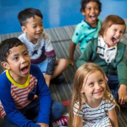 Young Students Sitting On Carpet Smiling