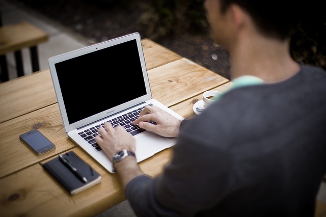A man using a computer at a park picnic table