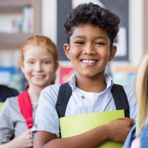 Portrait of happy children holding books and wearing backpack at elementary school.