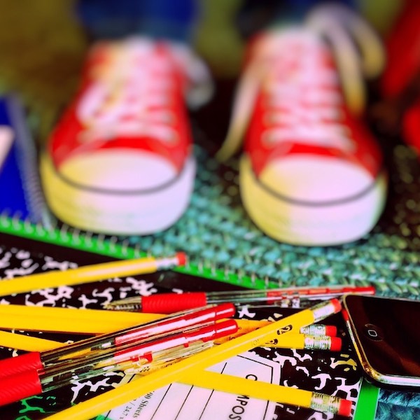 Kids sneakers standing in front ofpencils and school supplies