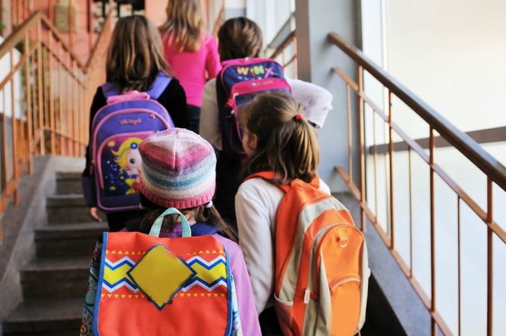 Group Of Girl Students Walking Up Stairs With Colorful Backpacks
