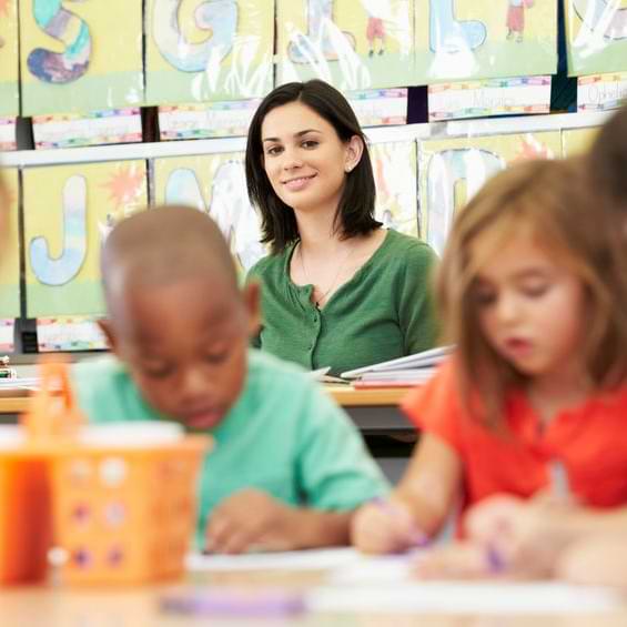 Female Teacher Smiling At Working Students